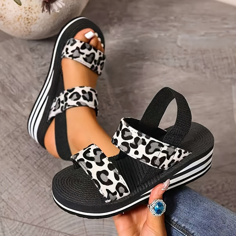 Black and white leopard-print women's platform wedge sandals with stretch straps, handheld and on-foot view