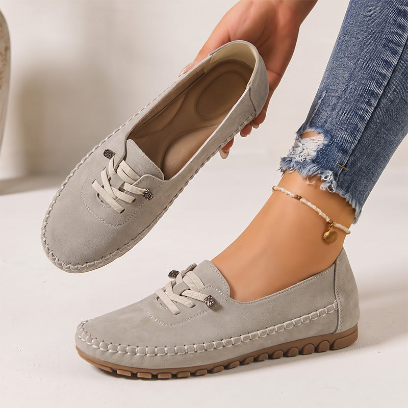 Light grey women's suede loafers showing the shaped insole and decorative lacing