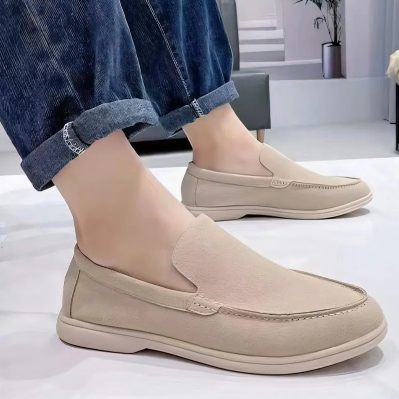 Light brown men's slip-on loafers worn with rolled jeans, side view