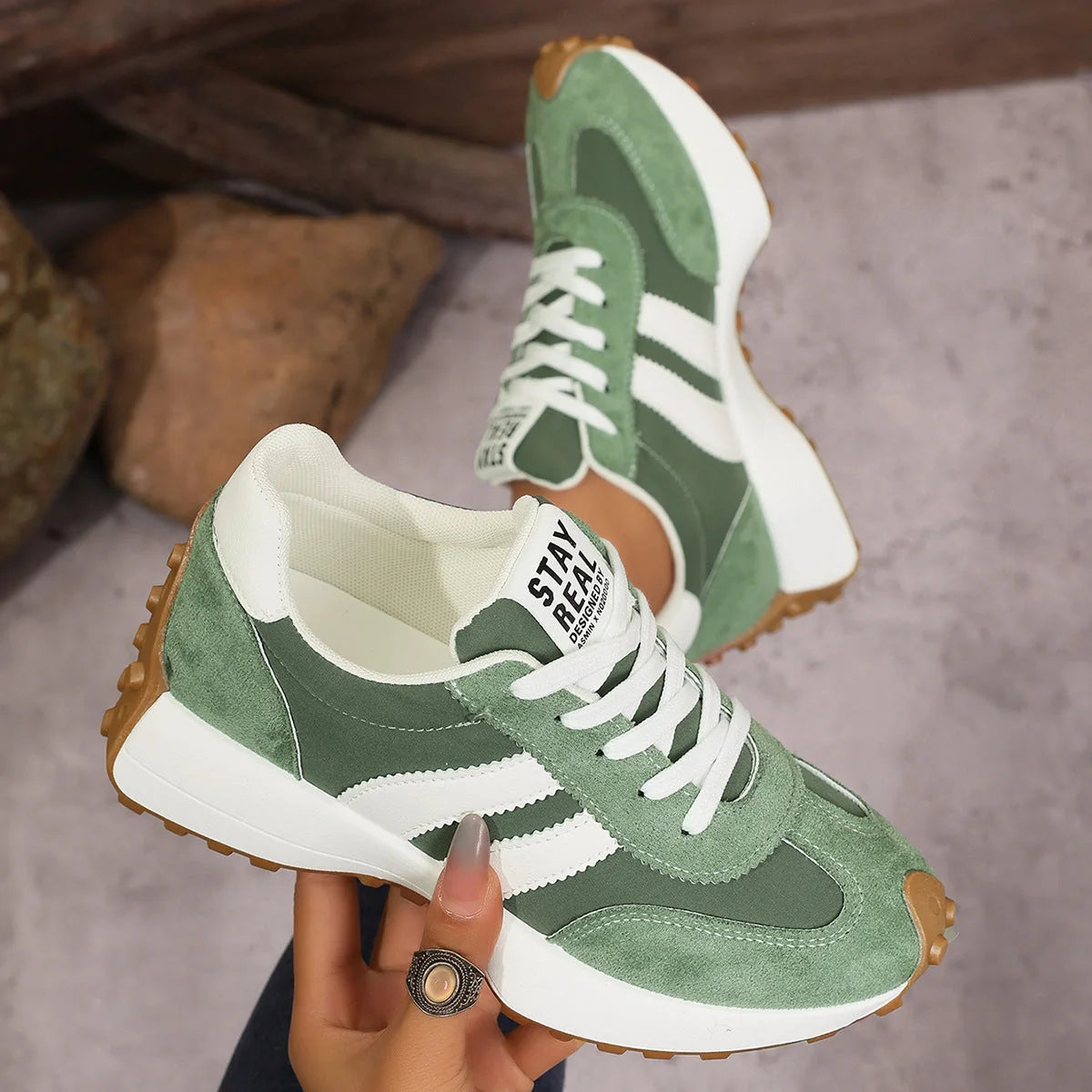 Women's green and white walking trainers shown on foot and held from the side